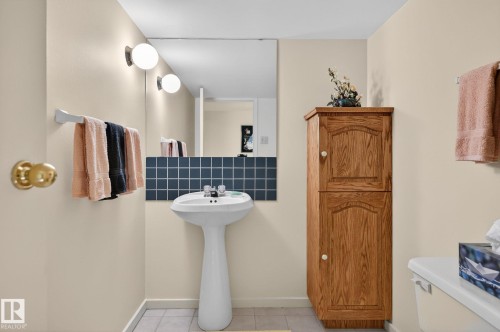 Pedestal sink with dual-handle faucet, full-width wall mirror, and a tiled backsplash - 848 Wheeler Road W, Edmonton, AB - Indoor Photo Showing Bathroom