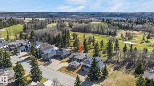 Property situated alongside a golf course, featuring a paved driveway, mature evergreen landscaping, and a multi-level roofline - 848 Wheeler Road W, Edmonton, AB - Outdoor With View