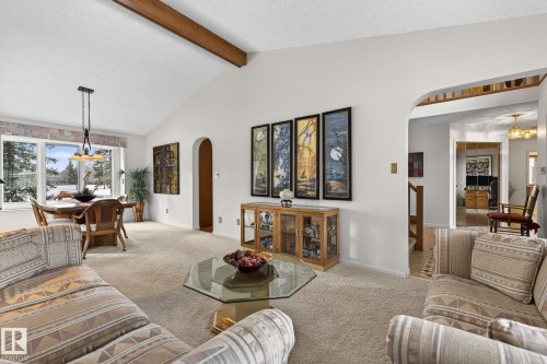 Vaulted ceiling with exposed wood beam, arched doorways, and dining area with large windows - 848 Wheeler Road W, Edmonton, AB - Indoor Photo Showing Living Room
