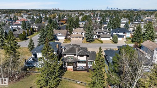 Contemporary residence featuring a dark shingled roof, a spacious rear deck, and mature evergreen trees - 848 Wheeler Road W, Edmonton, AB - Outdoor With View