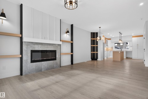 Spacious living area featuring wood-finish flooring and a fireplace with a stone-look surround and white mantel - 45 River Birch, St. Albert, AB - Indoor Photo Showing Living Room With Fireplace