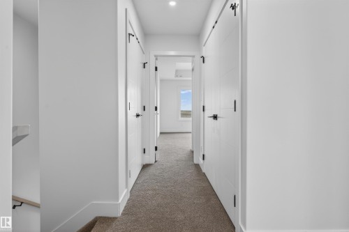 Hallway featuring white panel doors with matte black hardware, recessed lighting, and carpet flooring - 45 River Birch, St. Albert, AB - Indoor Photo Showing Other Room