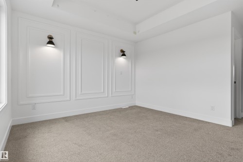 Carpeted interior space featuring decorative wall molding with integrated sconce lighting, white baseboards, and a tray ceiling - 45 River Birch, St. Albert, AB - Indoor Photo Showing Other Room