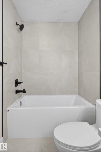 White tub and shower combination with matte black fixtures - 45 River Birch, St. Albert, AB - Indoor Photo Showing Bathroom