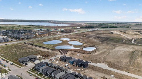 Aerial perspective of an expansive development area featuring multiple constructed residences and a large body of water in the background - 45 River Birch, St. Albert, AB - Outdoor With View