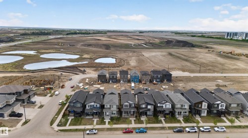 Residential street with a row of detached homes featuring varied exterior finishes and attached garages - 45 River Birch, St. Albert, AB - Outdoor With View