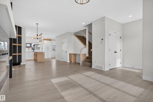 Expansive open-concept living area featuring wood-finish flooring, recessed lighting, and a modern chandelier - 45 River Birch, St. Albert, AB - Indoor