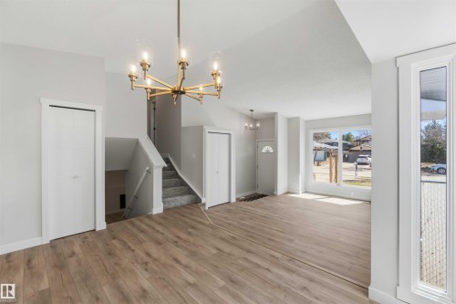 Open concept living space featuring wood-finish flooring, a contemporary chandelier, large picture window, and a staircase with carpeted treads - 119 Dorchester Drive, St. Albert, AB - Indoor Photo Showing Other Room