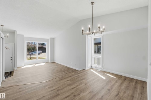Spacious room with wood-finish flooring, vaulted ceiling, and a contemporary chandelier - 119 Dorchester Drive, St. Albert, AB - Indoor Photo Showing Living Room