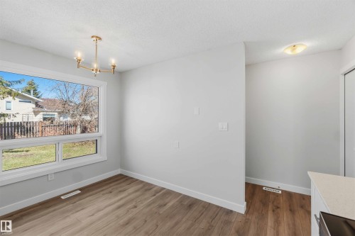 Spacious interior room featuring wood-finish flooring, a contemporary gold-tone chandelier, and a large window offering exterior views - 119 Dorchester Drive, St. Albert, AB - Indoor Photo Showing Other Room