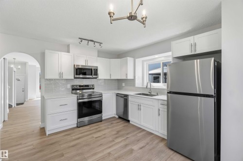 Kitchen featuring wood-finish flooring, white cabinetry, stainless steel appliances, light-toned countertops, and a subway tile backsplash - 119 Dorchester Drive, St. Albert, AB - Indoor Photo Showing Kitchen