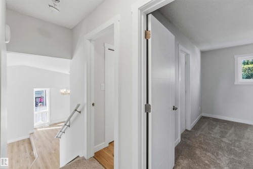 Upper level hallway featuring light gray walls, modern panel doors with black hardware, and carpet flooring - 119 Dorchester Drive, St. Albert, AB - Indoor Photo Showing Other Room