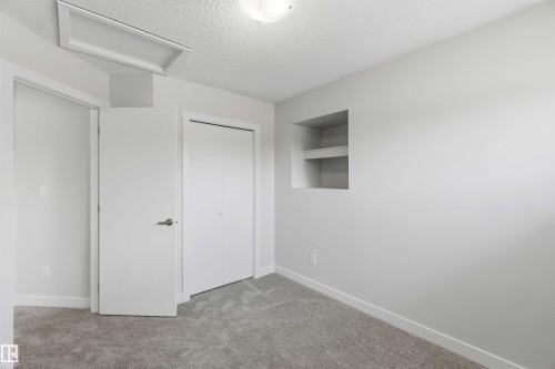 Carpeted interior space featuring light gray walls, a built-in recessed niche with shelving, and a flush-mount ceiling light - 119 Dorchester Drive, St. Albert, AB - Indoor Photo Showing Other Room