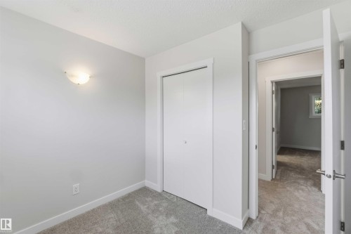 Neutral-toned room featuring light gray walls, plush gray carpeting, white baseboards, and a white bi-fold closet door - 119 Dorchester Drive, St. Albert, AB - Indoor Photo Showing Other Room