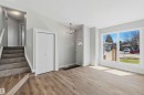 Bright living space featuring wood-finish flooring, a contemporary chandelier, large picture windows, a front entry door with a decorative glass insert, and a stairway with carpeted treads - 119 Dorchester Drive, St. Albert, AB  - Indoor Photo Showing Other Room 