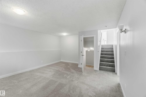 Carpeted room with a staircase featuring a white handrail and a neutral color palette - 119 Dorchester Drive, St. Albert, AB - Indoor Photo Showing Other Room