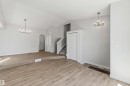 Vaulted ceiling great room with wood-finish flooring, staircase with carpeted treads, and two contemporary chandeliers - 119 Dorchester Drive, St. Albert, AB  - Indoor 