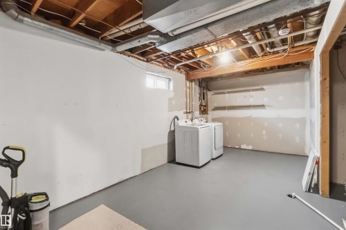Basement area featuring a washer and dryer setup, painted concrete flooring, and exposed ceiling joists - 119 Dorchester Drive, St. Albert, AB - Indoor