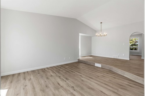Bright interior featuring wood-finish flooring, vaulted ceilings, a chandelier, and an arched doorway - 119 Dorchester Drive, St. Albert, AB - Indoor Photo Showing Other Room