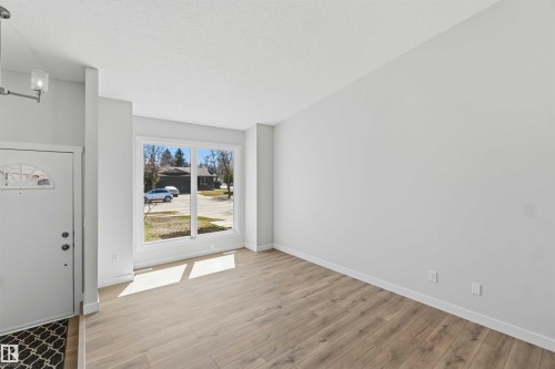 Entryway featuring a white paneled door with an arched glass insert, wood-finish flooring, and a contemporary ceiling light fixture - 119 Dorchester Drive, St. Albert, AB - Indoor Photo Showing Other Room