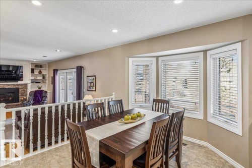 This dining area features a dark wood table with matching chairs, tiled flooring, and a bay window providing natural light - 954 Rice Road, Edmonton, AB - Indoor Photo Showing Dining Room