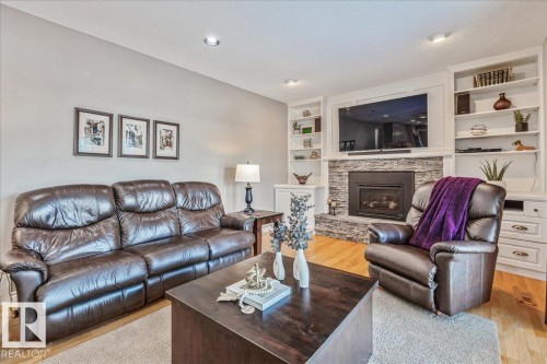 Living area featuring light hardwood flooring, a stone fireplace, and built-in white shelving - 954 Rice Road, Edmonton, AB - Indoor Photo Showing Living Room With Fireplace