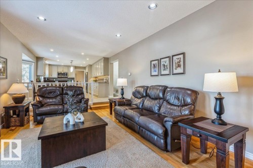Spacious living area featuring recessed lighting, hardwood flooring, and an open view into the kitchen area with its light-colored cabinetry and dark appliances - 954 Rice Road, Edmonton, AB - Indoor Photo Showing Living Room