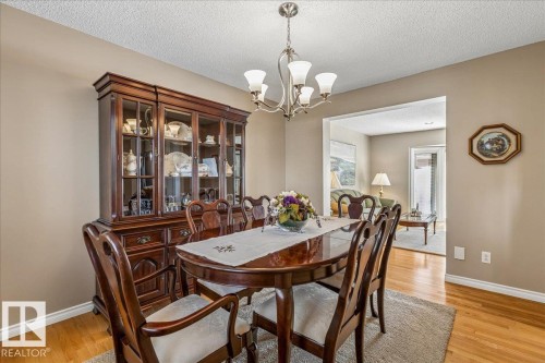 The dining area features hardwood flooring, a chandelier light fixture, and an open entryway to an additional living space - 954 Rice Road, Edmonton, AB - Indoor Photo Showing Dining Room
