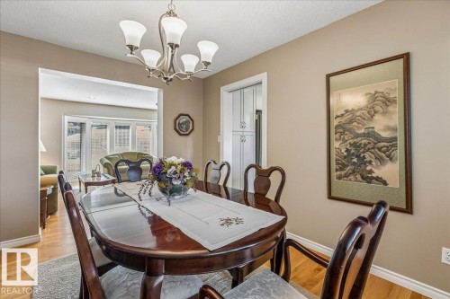 The dining area features hardwood floors and a chandelier, with access to an additional living space with a bay window - 954 Rice Road, Edmonton, AB - Indoor Photo Showing Dining Room
