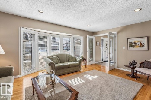 Living room featuring hardwood floors, a large area rug, and a bay window with blinds - 954 Rice Road, Edmonton, AB - Indoor Photo Showing Living Room