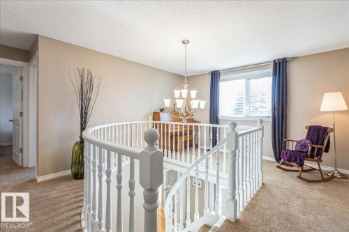 This landing features light-colored carpet, a white balustrade, and a window with blinds and dark blue curtains - 954 Rice Road, Edmonton, AB - Indoor Photo Showing Other Room