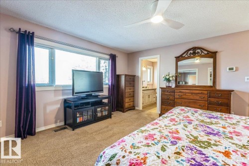 The room features carpeted flooring, a ceiling fan, and a wide window with blinds - 954 Rice Road, Edmonton, AB - Indoor Photo Showing Bedroom