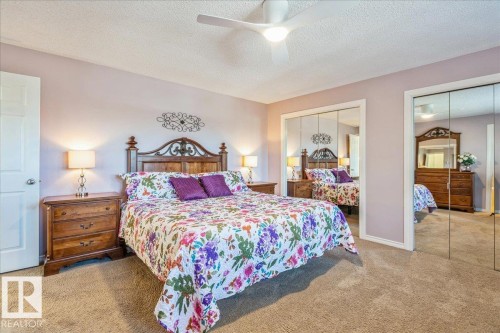 The property features a bedroom with a ceiling fan, plush carpeting, and two mirrored closet doors - 954 Rice Road, Edmonton, AB - Indoor Photo Showing Bedroom