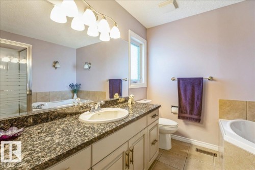 The bathroom features a vanity with a granite countertop and an integrated sink, a toilet, and a bathtub - 954 Rice Road, Edmonton, AB - Indoor Photo Showing Bathroom