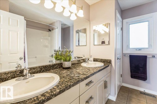 This bathroom features a double vanity with granite countertops and two sinks - 954 Rice Road, Edmonton, AB - Indoor Photo Showing Bathroom