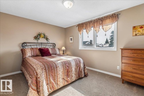 This room features neutral-toned walls, a window with a valance, and wall-to-wall carpeting - 954 Rice Road, Edmonton, AB - Indoor Photo Showing Bedroom