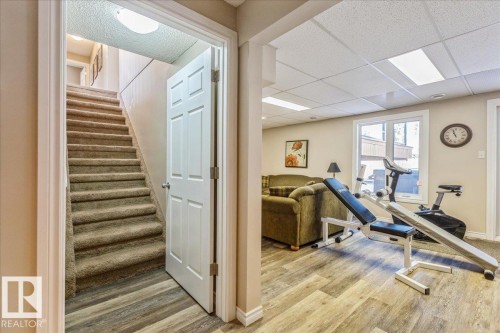 Open doorway leading to a carpeted staircase and a room with wood-look flooring and a window - 954 Rice Road, Edmonton, AB - Indoor Photo Showing Gym Room