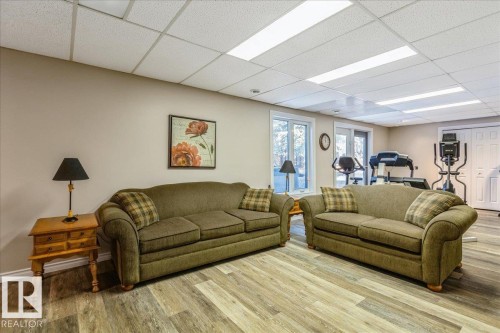 The property features light-toned walls, a drop ceiling with integrated lighting, and wood-look flooring - 954 Rice Road, Edmonton, AB - Indoor