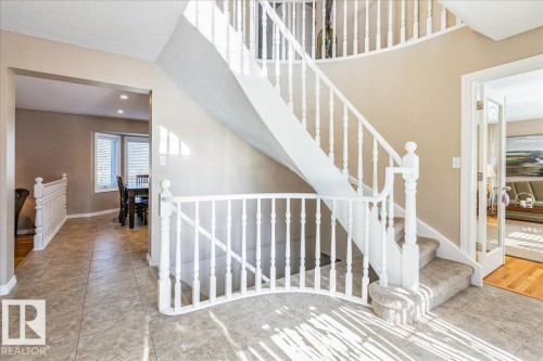 The entryway features a curved staircase with white banisters and carpeted steps - 954 Rice Road, Edmonton, AB - Indoor Photo Showing Other Room