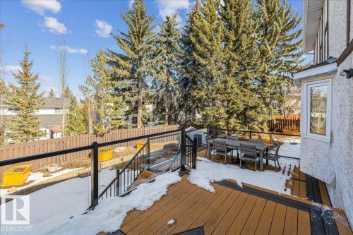 The property features a spacious outdoor deck with a glass and metal railing, overlooking a fenced yard - 954 Rice Road, Edmonton, AB - Outdoor