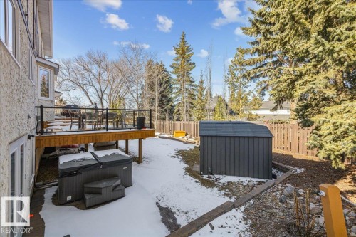 The property features a raised outdoor deck with glass railings, a storage shed, and a fenced yard with mature trees - 954 Rice Road, Edmonton, AB - Outdoor With Deck Patio Veranda