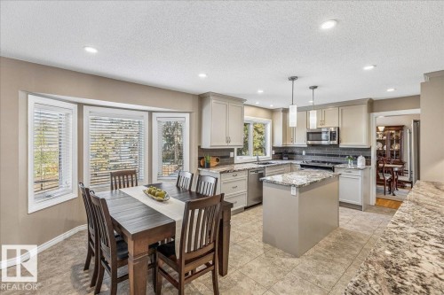 The kitchen features a central island with a granite countertop, stainless steel appliances, and ample cabinetry - 954 Rice Road, Edmonton, AB - Indoor