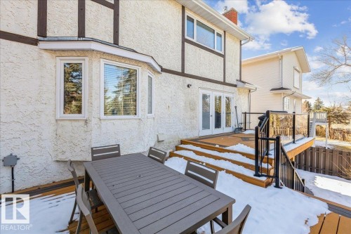 The property features a stucco exterior with decorative dark wood accents, an outdoor deck area with glass panel railings, and a bay window - 954 Rice Road, Edmonton, AB - Outdoor With Deck Patio Veranda With Exterior