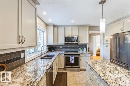 The kitchen features light-colored cabinetry, stainless steel appliances, a double basin sink, and granite countertops - 954 Rice Road, Edmonton, AB - Indoor Photo Showing Kitchen With Stainless Steel Kitchen With Double Sink With Upgraded Kitchen