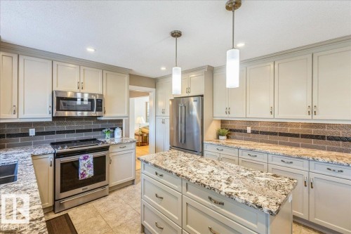 The kitchen features extensive cabinetry, stainless steel appliances, a tiled backsplash, and granite countertops - 954 Rice Road, Edmonton, AB - Indoor Photo Showing Kitchen With Stainless Steel Kitchen With Upgraded Kitchen
