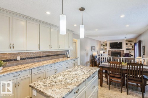 The kitchen features extensive cabinetry, granite countertops, and a tiled backsplash - 954 Rice Road, Edmonton, AB - Indoor