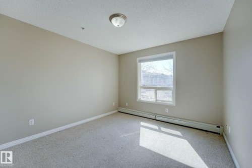 Carpeted room featuring a window with white trim, a semi-flush mount ceiling light, and baseboard heating - 7226 7327 South Terwillegar Drive, Edmonton, AB - Indoor Photo Showing Other Room