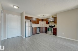 Kitchen area featuring dark wood-finish cabinetry, stainless steel appliances, and a light-toned backsplash - 