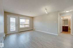 Spacious living area featuring light wood-finish flooring, neutral wall tones, and recessed track lighting - 