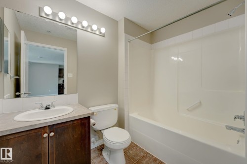 Bathroom featuring a vanity with dark wood-finish cabinetry, a single basin sink, and a light-toned countertop - 7226 7327 South Terwillegar Drive, Edmonton, AB - Indoor Photo Showing Bathroom